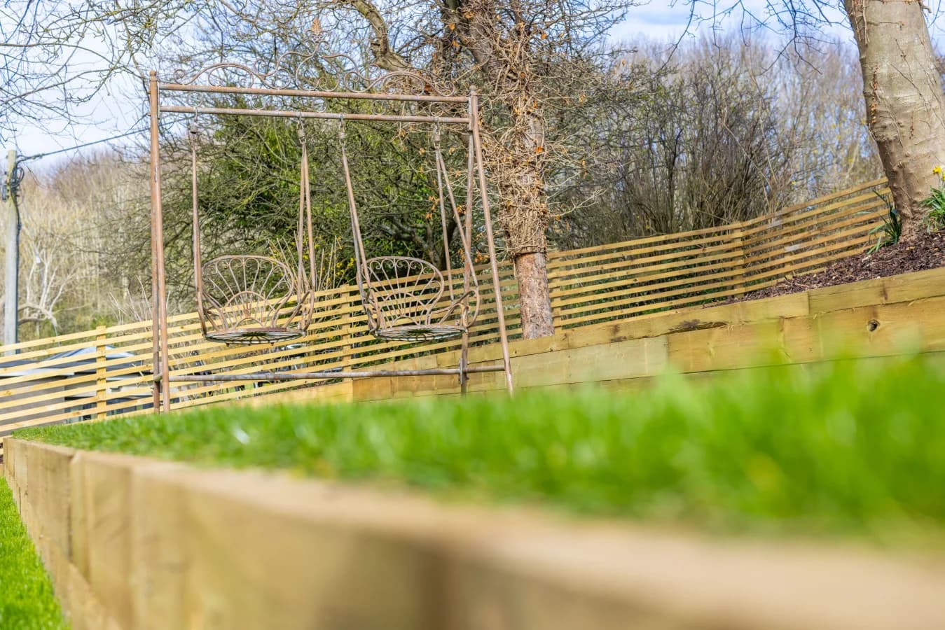 Garden swing set within a landscaped lawn and timber-fenced garden