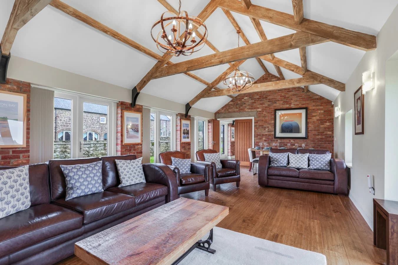 Spacious lounge with leather sofas and characterful barn features