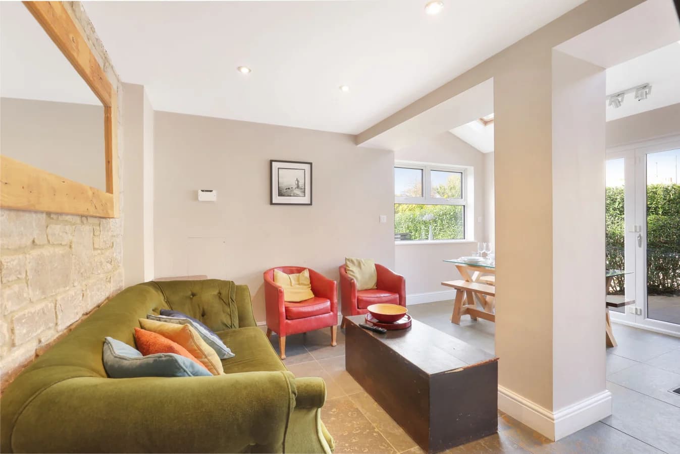 Cosy snug with green velvet sofa, exposed stone wall and armchairs