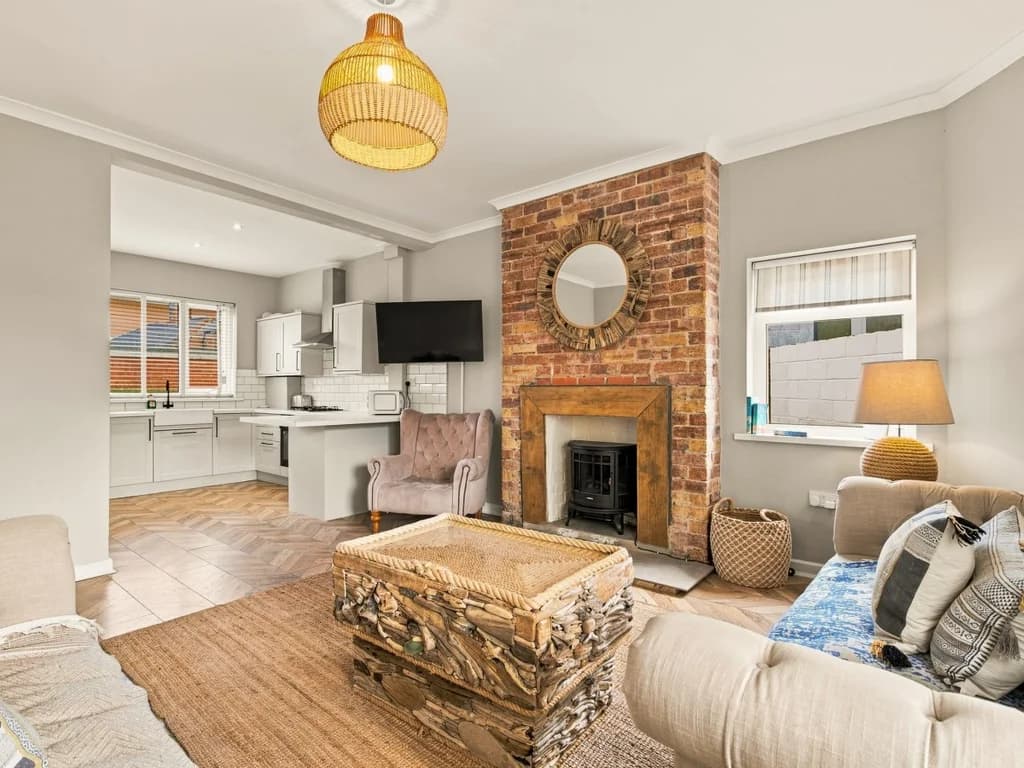 Open-plan lounge with exposed brick fireplace and breakfast bar.