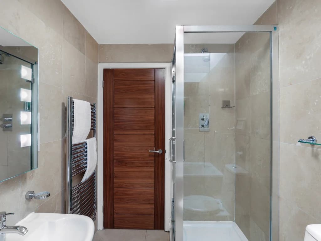 Bathroom with glass shower enclosure and illuminated mirror