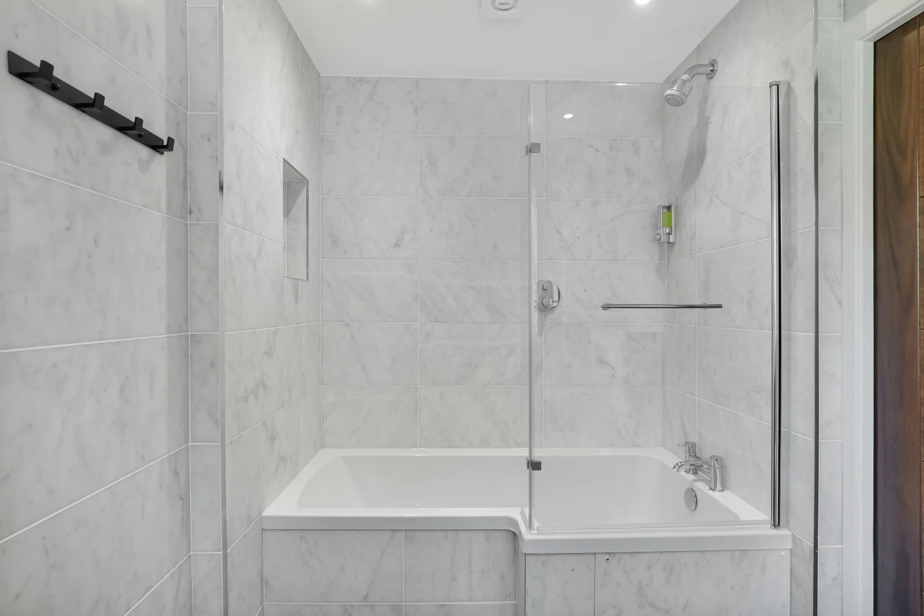 Family bathroom with marble-effect wall tiles and bath-shower