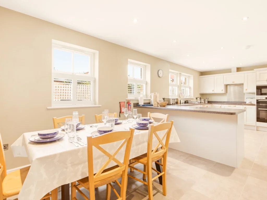 Spacious open-plan dining area with seating for six beside the kitchen