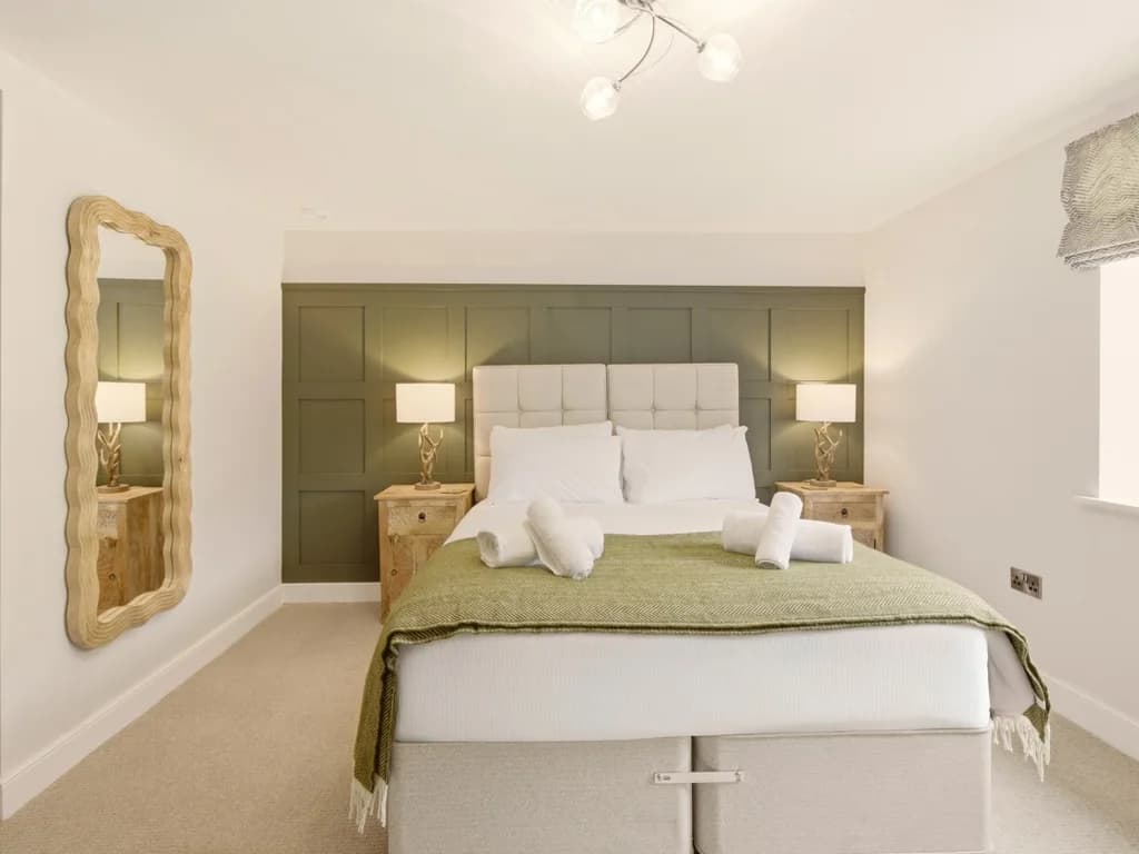 Elegant king bedroom with panelled feature wall and bedside lighting