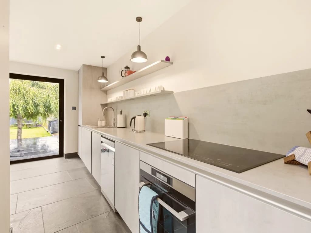 Bright galley kitchen with integrated appliances and garden views.