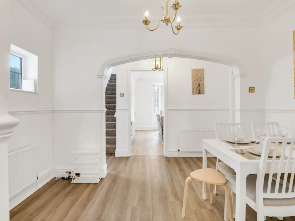 Dining area with table and chairs, decorative archway and staircase