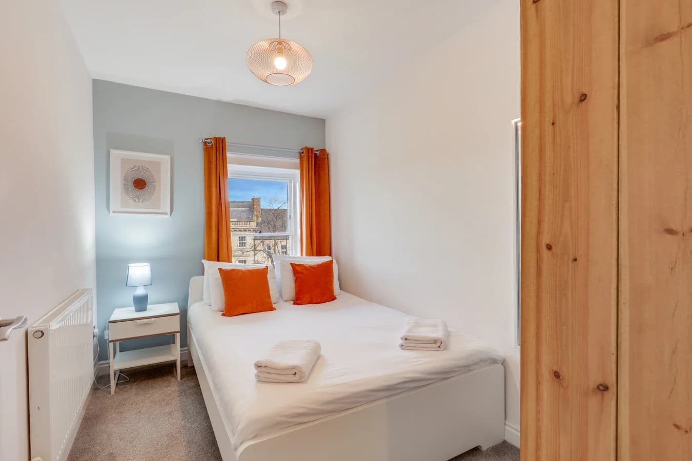 Comfortable guest bedroom with warm orange accents and soft blue tones