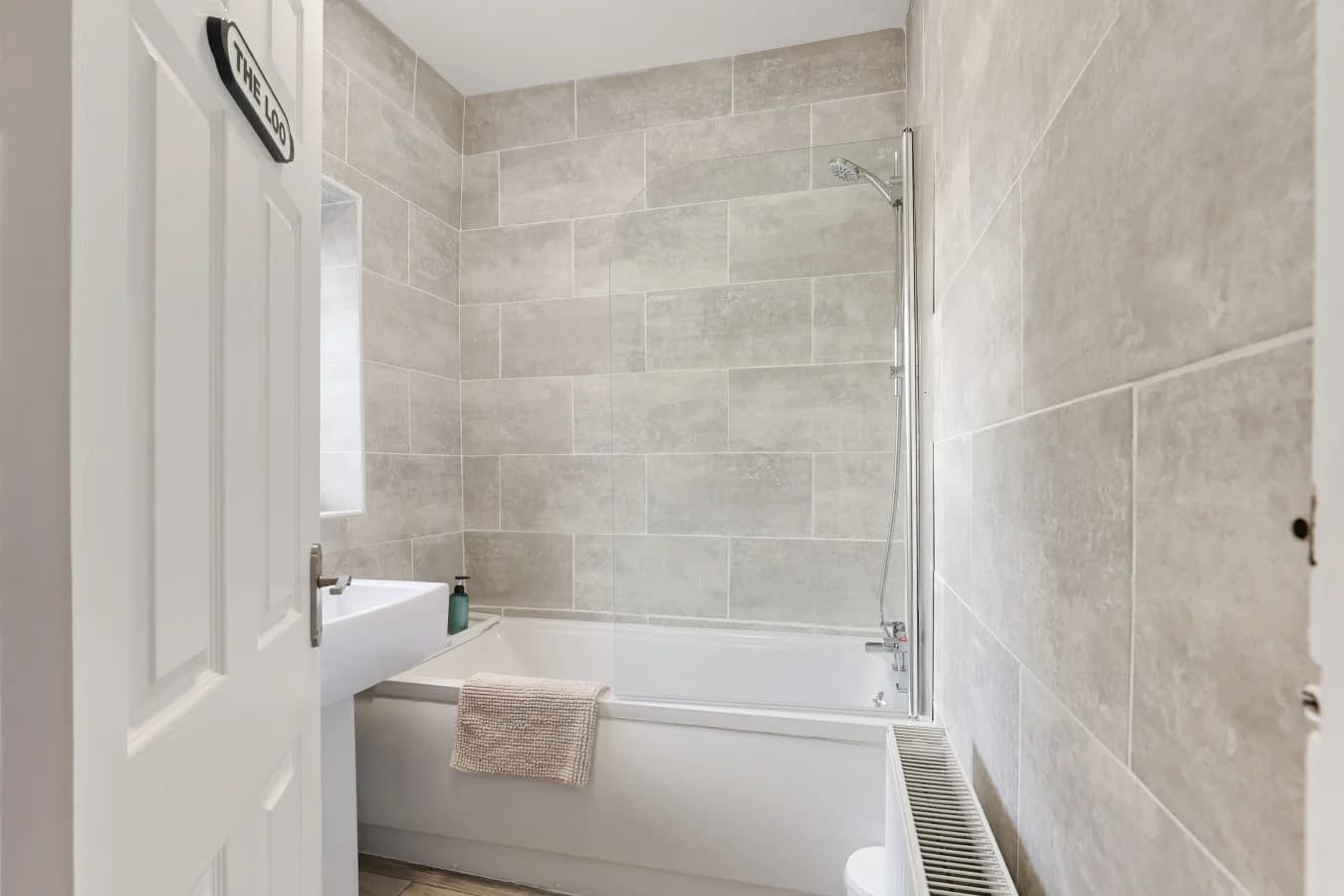 Contemporary family bathroom with grey stone-effect tiling and bath