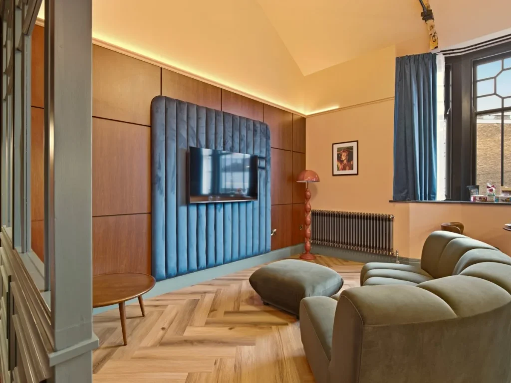 Living area with curved sofa, Smart TV and large bay window.