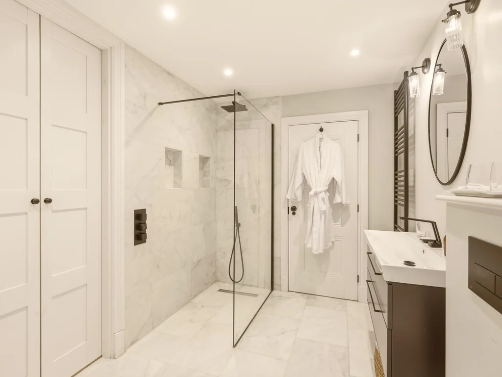 En-suite shower room with marble-effect walls, walk-in shower and vanity