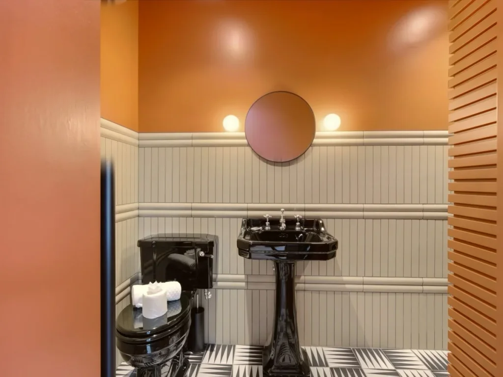 Contemporary bathroom with black fittings, round mirror and wall lights.