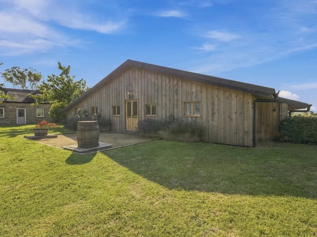 Timber-clad Big Barn exterior surrounded by lawn and mature planting