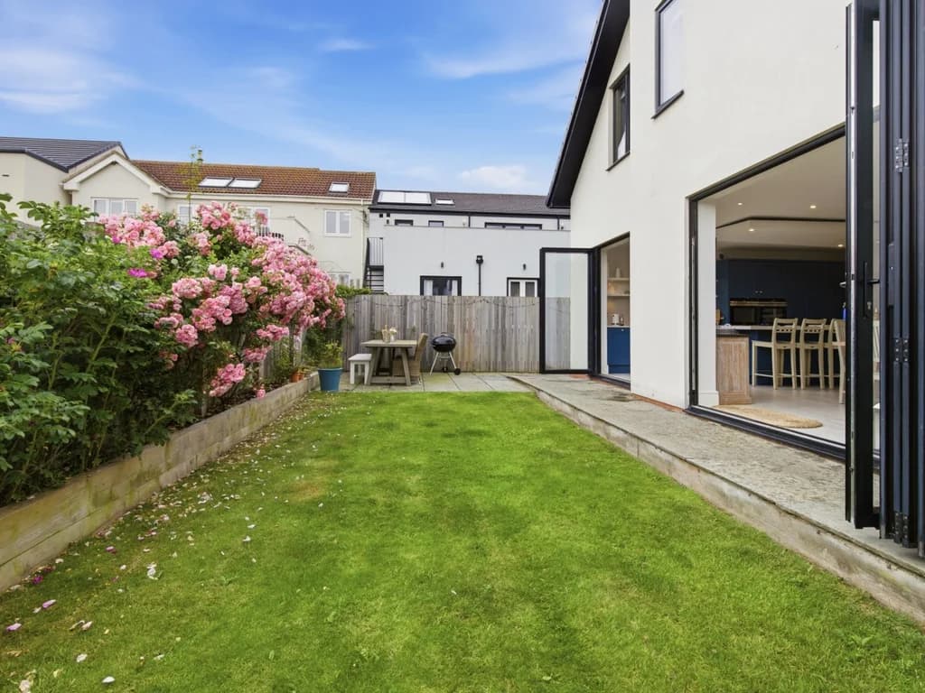 Enclosed rear garden with lawn and bi-fold doors to the living area