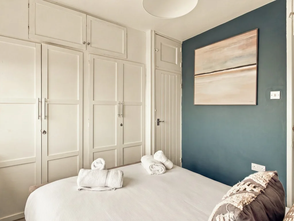 King bedroom with fitted wardrobes and blue feature wall.