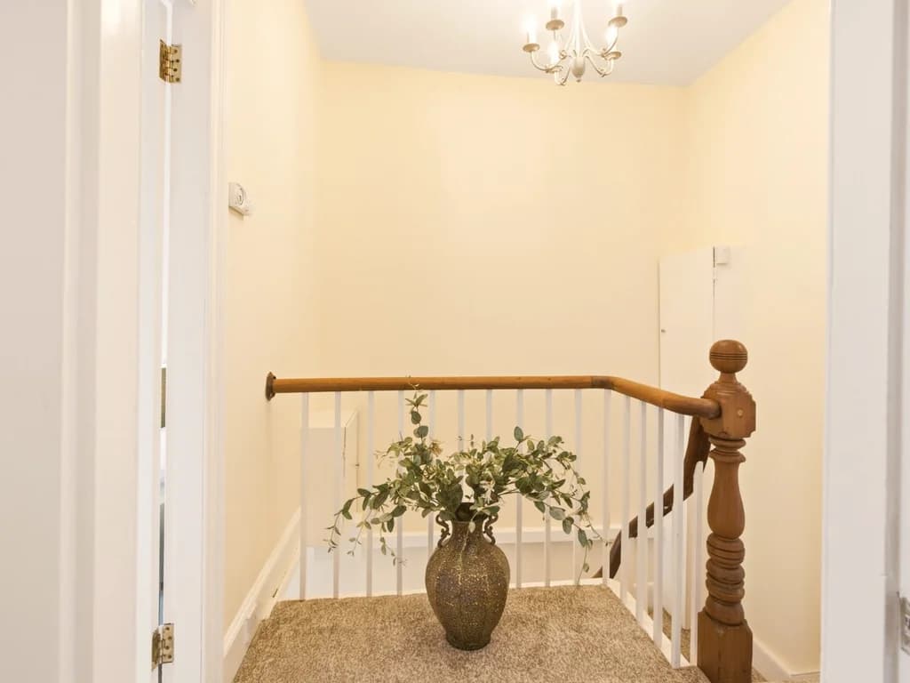 First-floor landing with wooden handrail and decorative greenery.