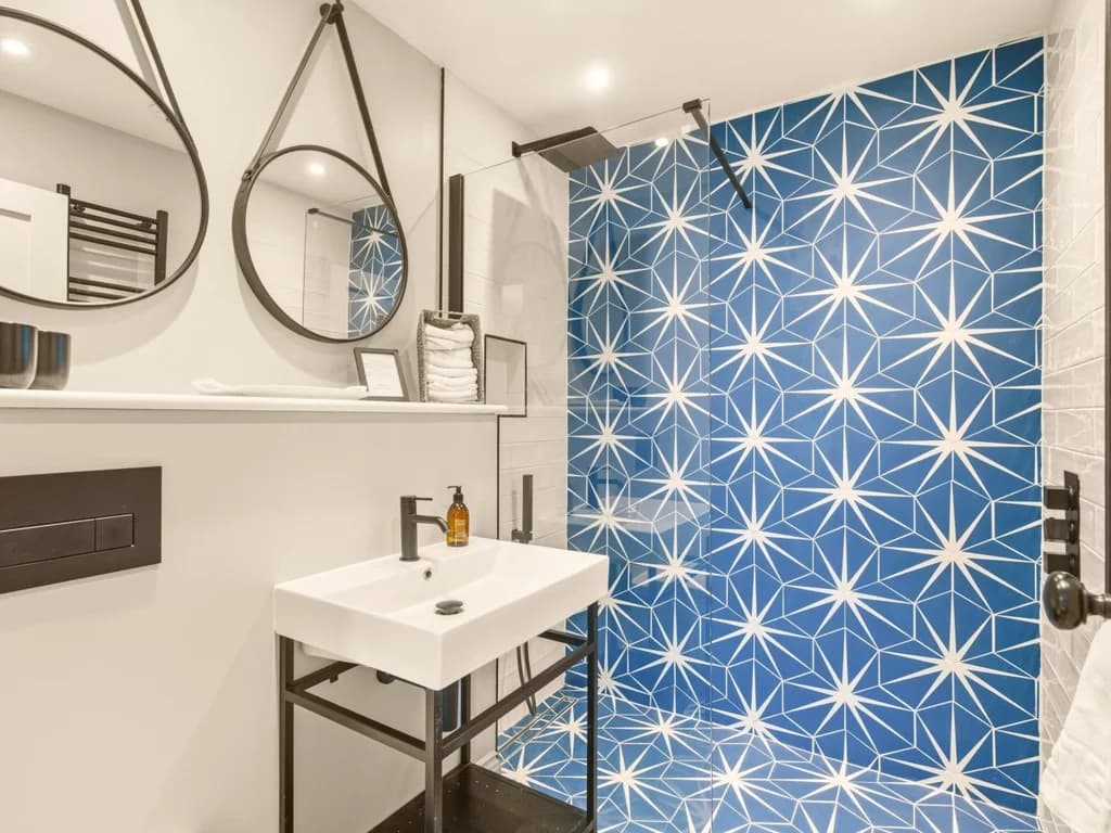 En-suite shower room with blue geometric feature tiles and black fittings
