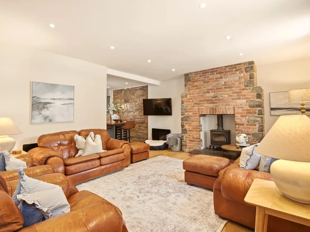 Spacious living room with leather sofas and feature fireplace.