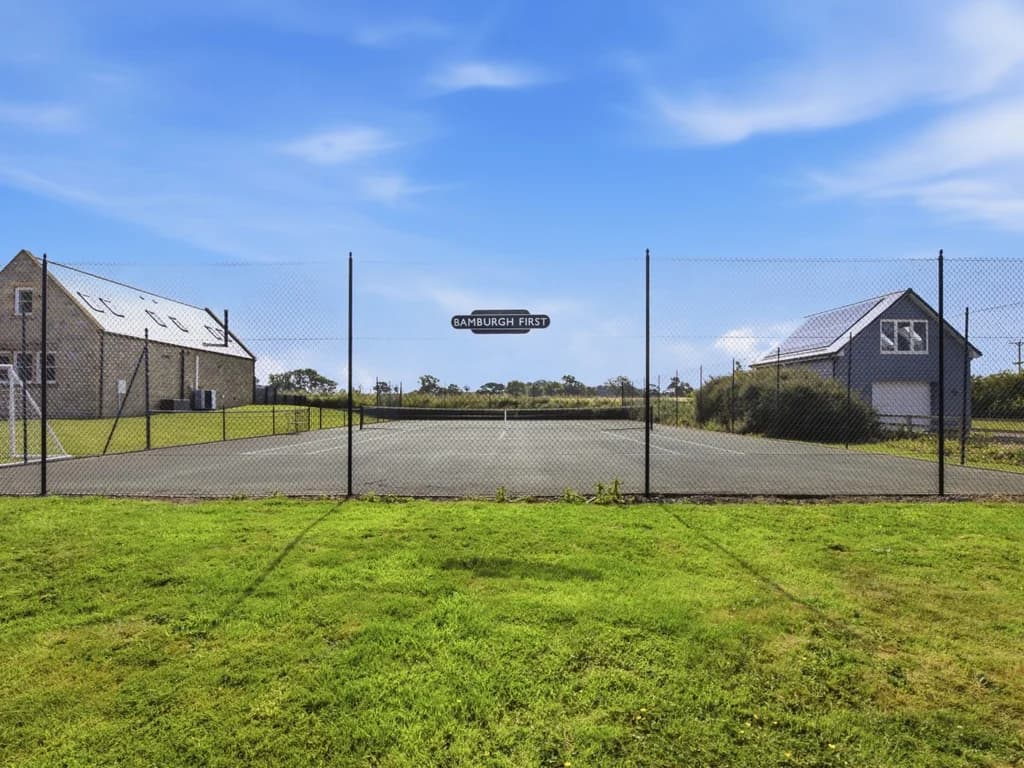 Shared fenced tennis court beside the cottage grounds