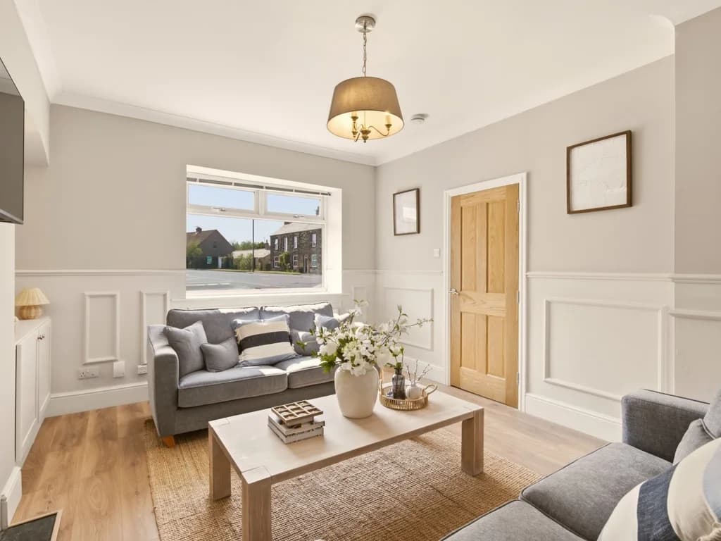 Lounge with feature wall panelling, wooden coffee table and bay window