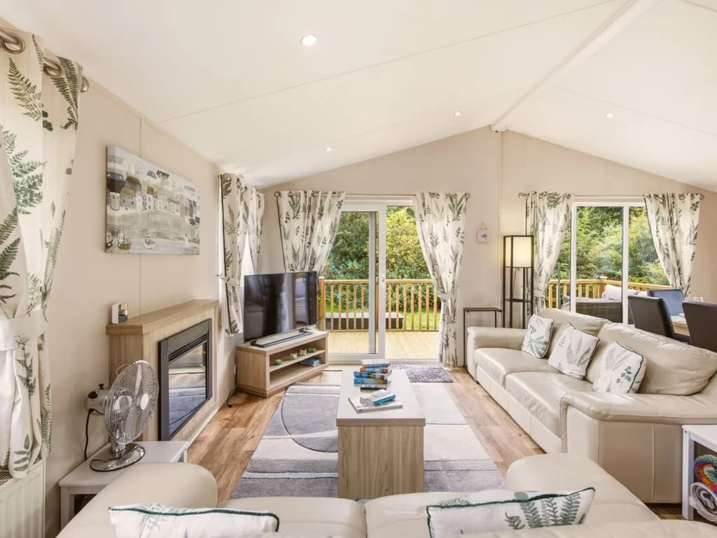 Spacious lounge with sofas, TV, fireplace and doors onto the decking