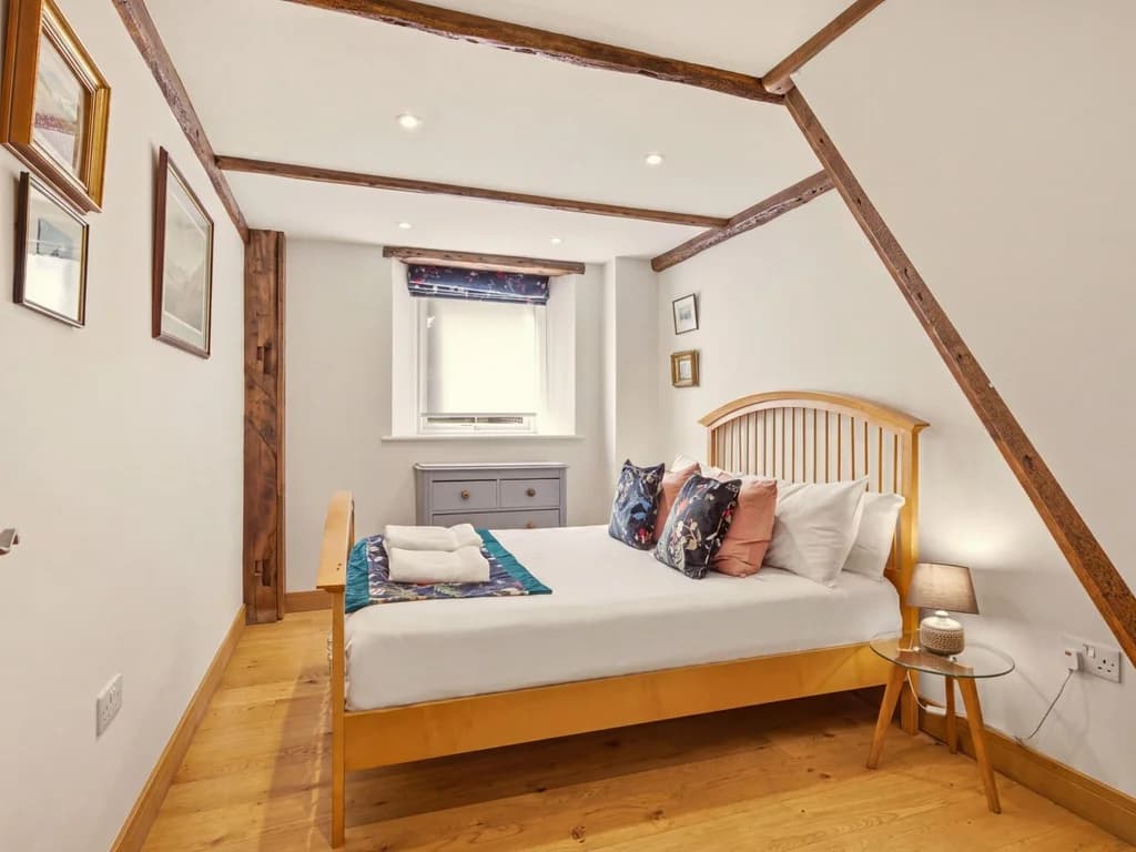 Bright bedroom with wooden bed frame and exposed timber details
