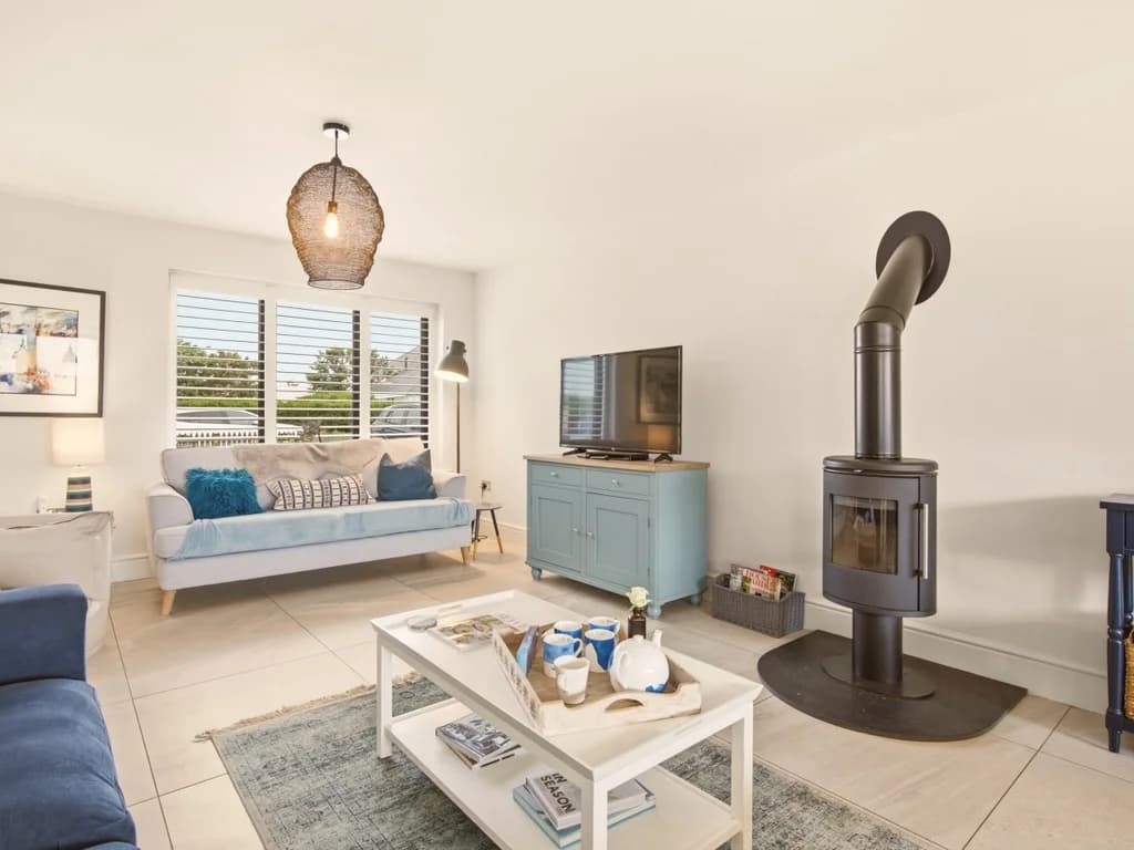 Open-plan lounge with freestanding wood burner and plantation shutter window