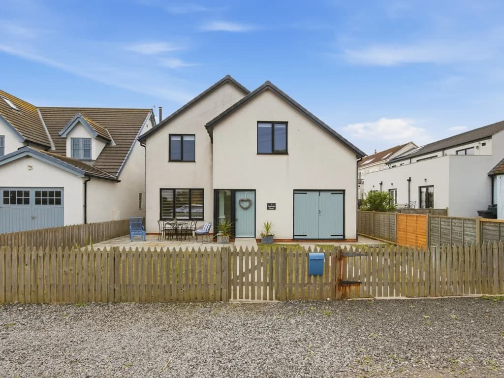 Front elevation with enclosed garden, driveway and garage door