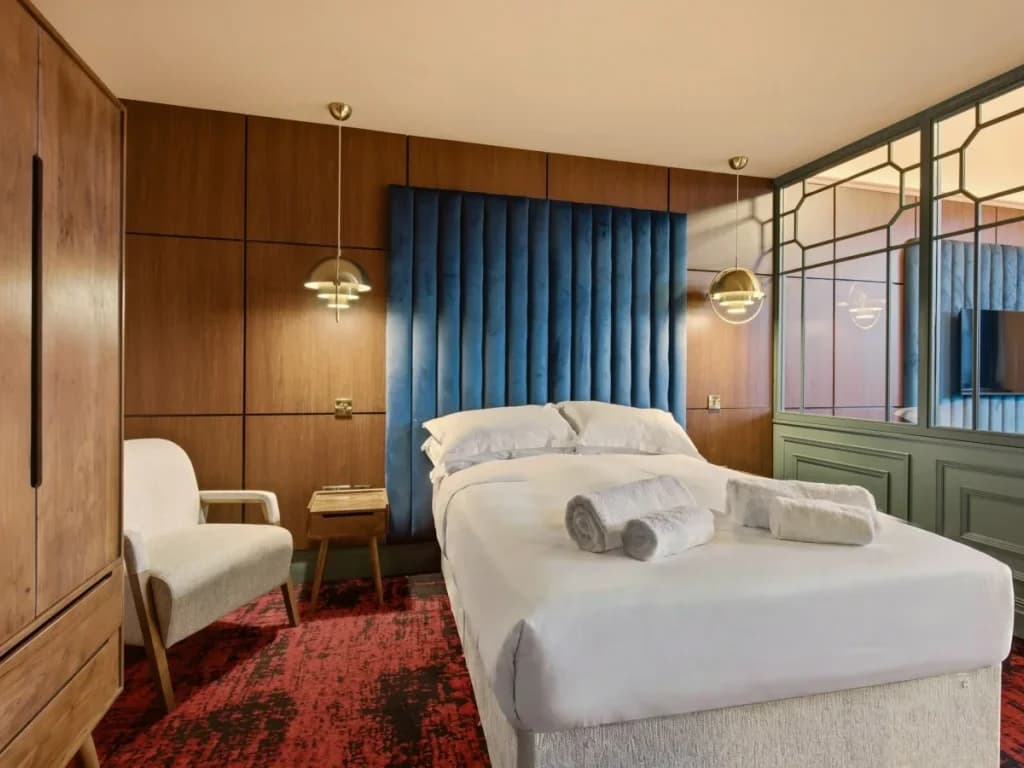 Double bed with tall blue headboard, wardrobe and decorative screen.