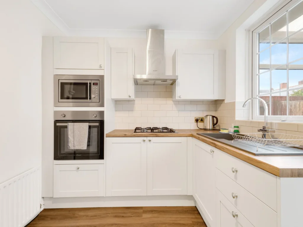 Modern kitchen with oven, gas hob, microwave and bright window light