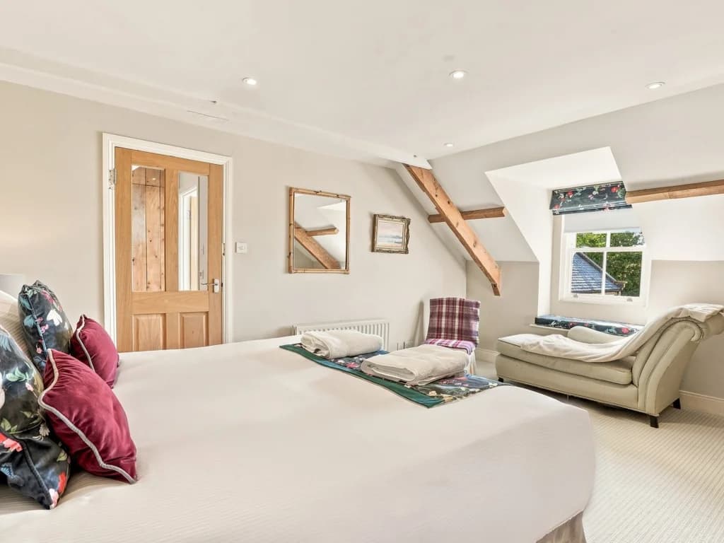 Spacious king bedroom with seating area and exposed timber beams