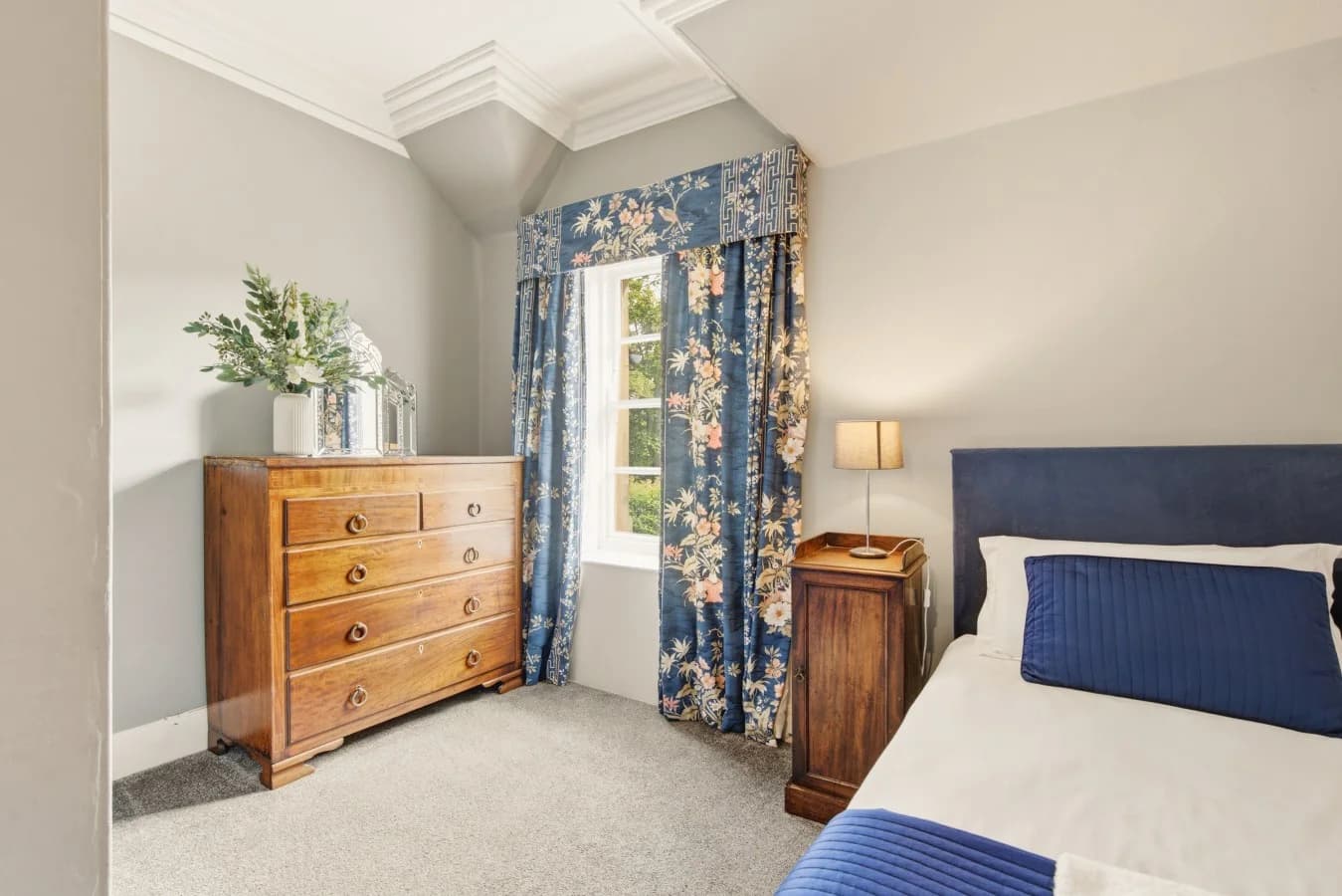 Twin bedroom with wooden dresser, blue accents and natural light