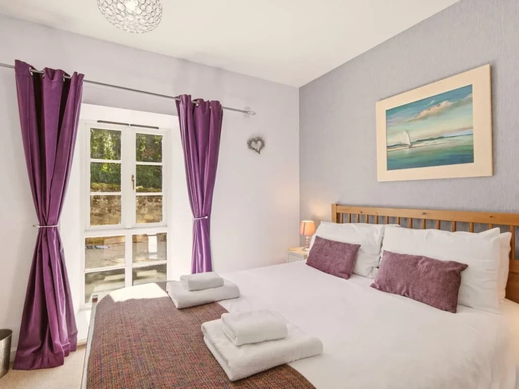 King bedroom with purple accents, bedside lighting and outdoor outlook