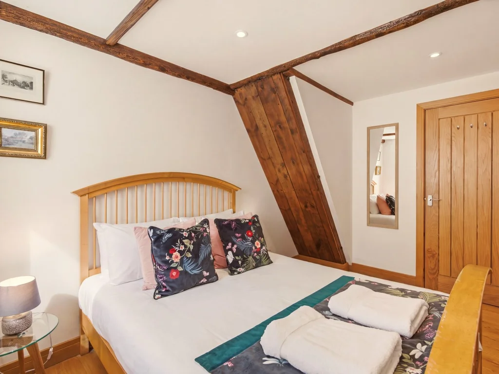 Comfortable bedroom with wooden bed frame and original timber beams