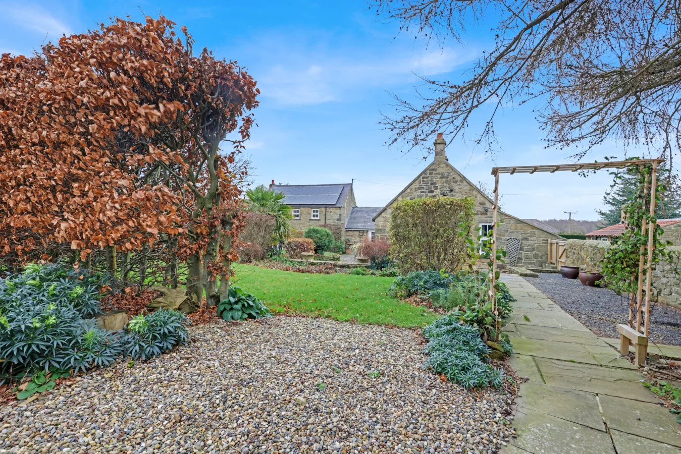 Landscaped grounds with ornamental planting and orchard beyond