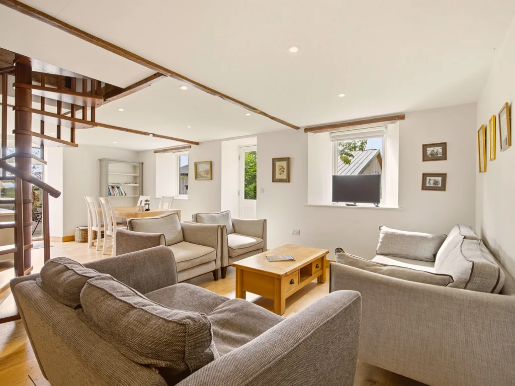 Spacious lounge with sofas, TV and spiral staircase
