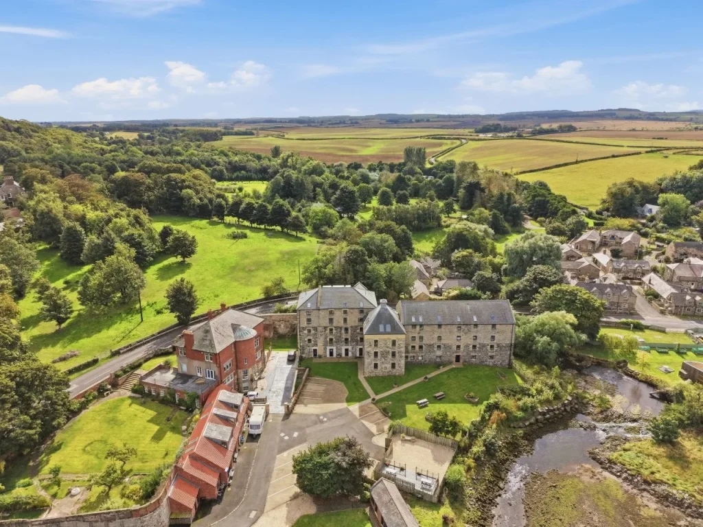 Elevated view of Waren Mill with green fields and woodland beyond