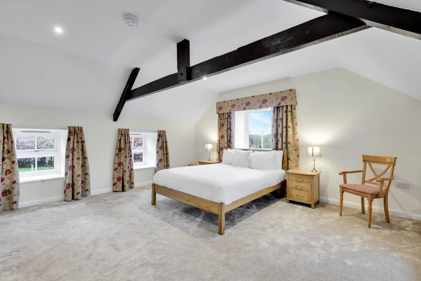 Characterful bedroom with floral drapes and exposed roof timbers