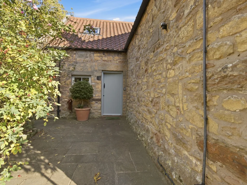 Side entrance and paved pathway beside Spitalford's stone walls