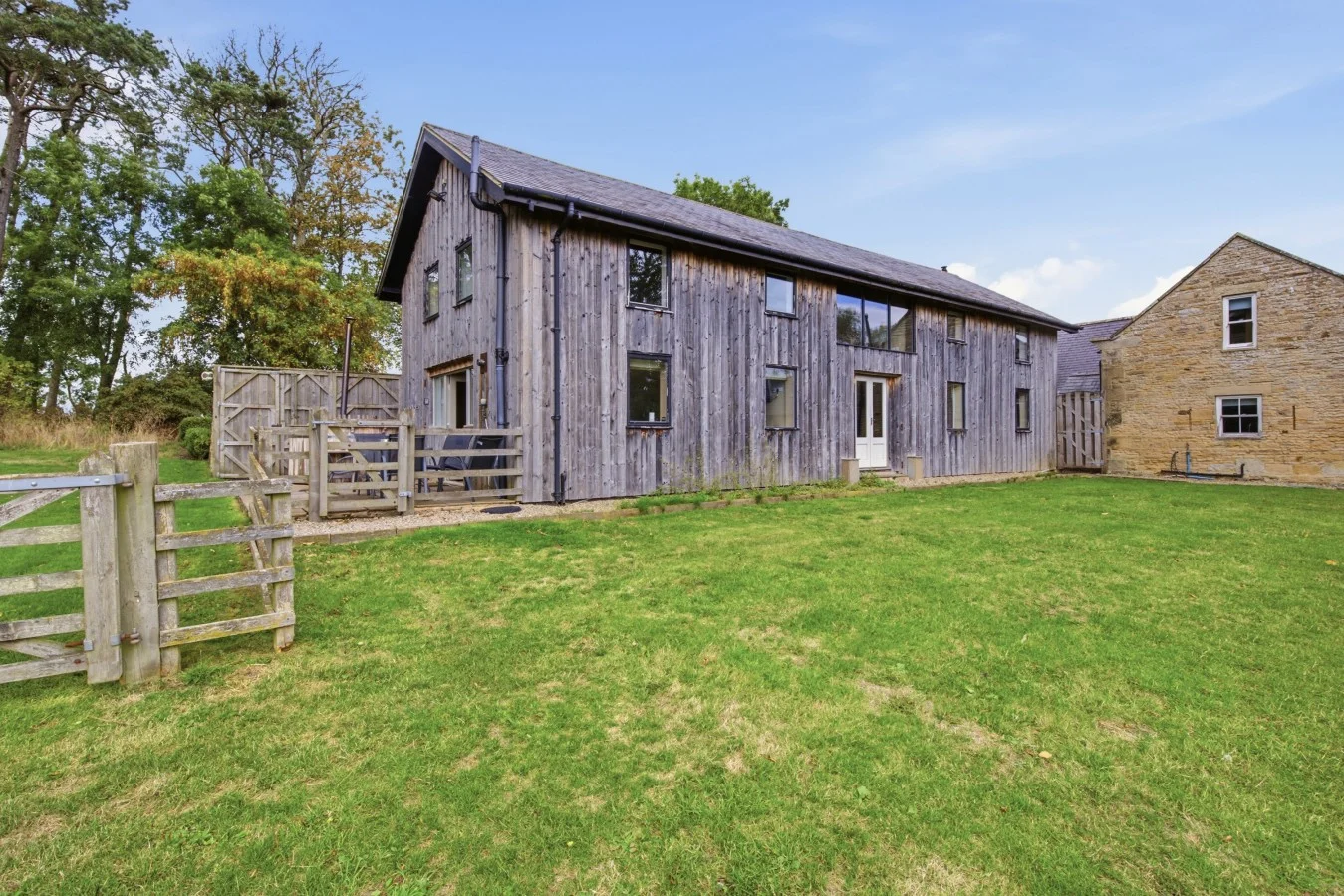 Timber-clad Drum Barn surrounded by open lawns and countryside