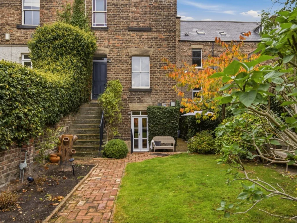 Private garden with lawn, paved seating area and leafy borders