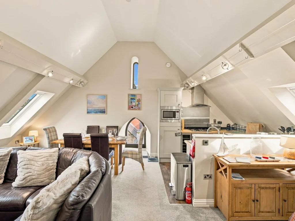 Open-plan living area with skylights, dining table and fitted kitchen.