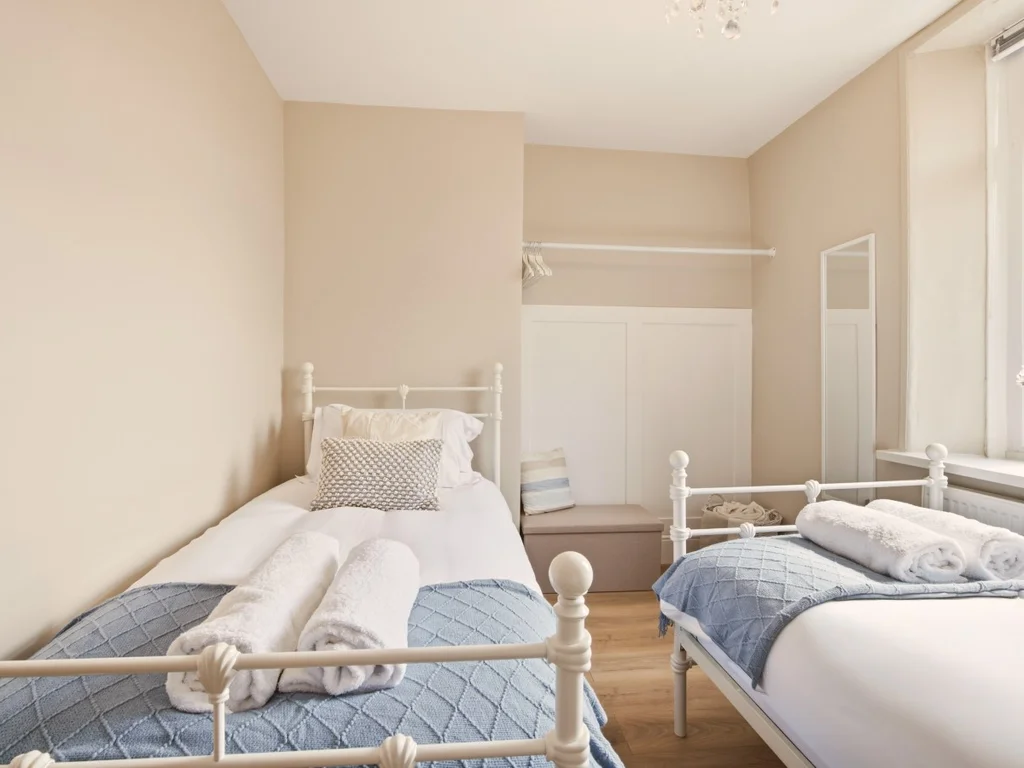 Bright twin bedroom with two single beds and large window.