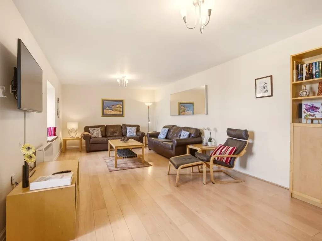 Spacious living area with leather seating, bookshelves and wooden flooring
