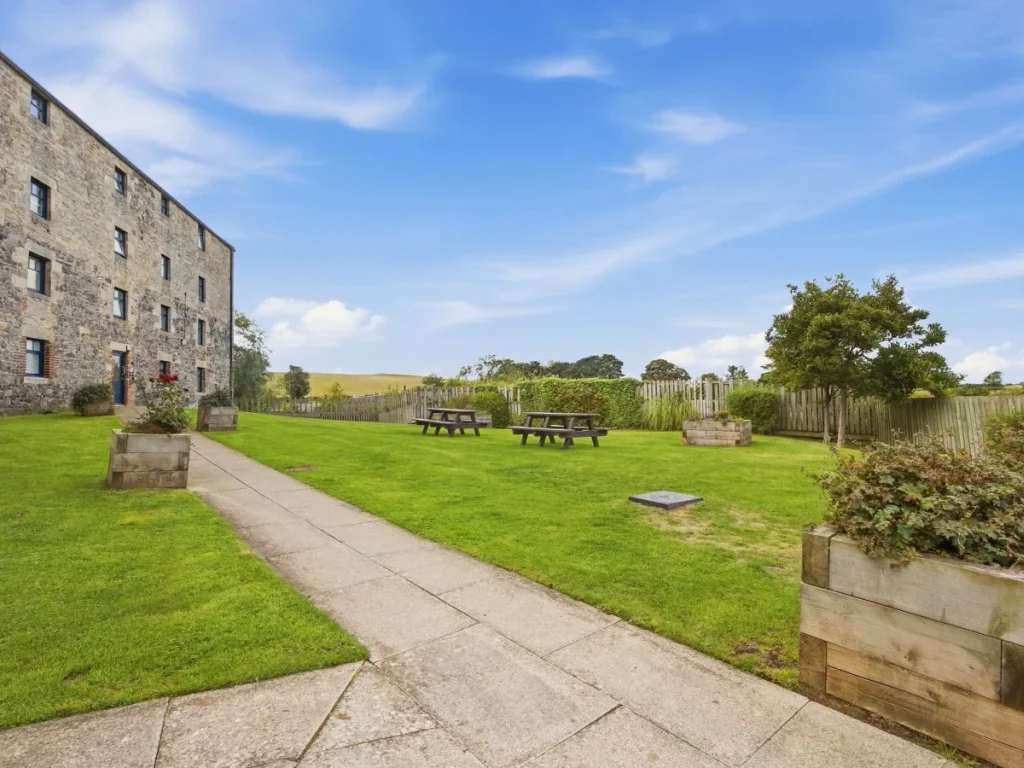 Shared garden with picnic tables, open lawns and countryside beyond