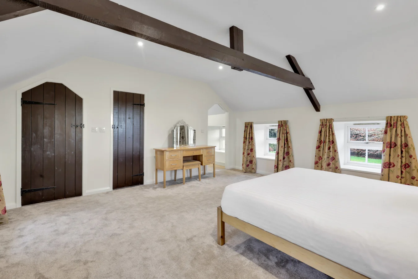 Spacious king bedroom beneath vaulted ceilings and exposed beams