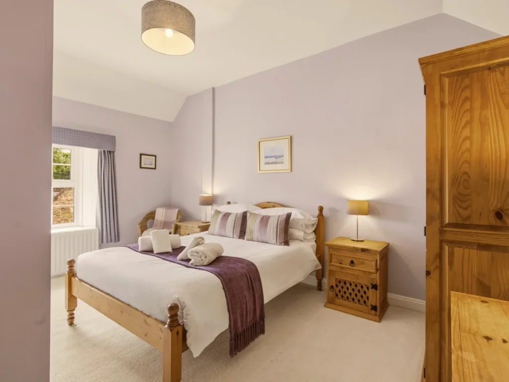 Comfortable double bedroom with oak wardrobe, bedside tables and armchair