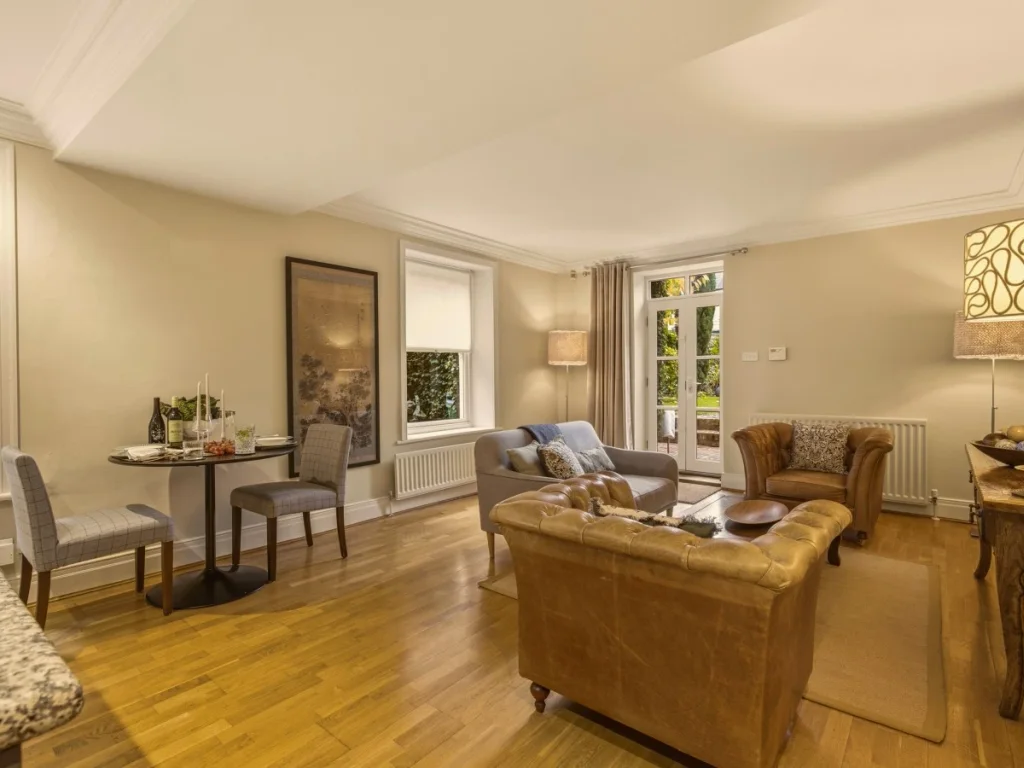 Living and dining area with warm wood flooring and garden views