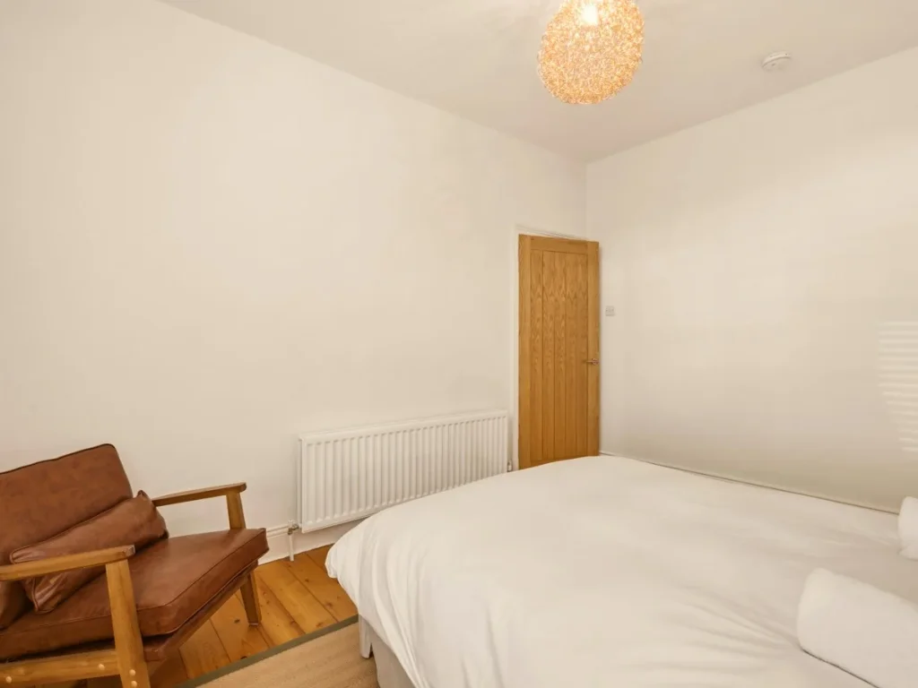 King-size bedroom with wooden flooring, chair and plenty of open space