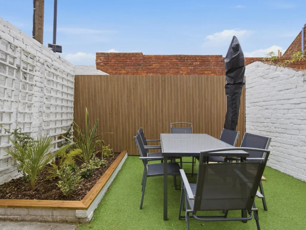 Enclosed outdoor space with dining table, seating and planted borders