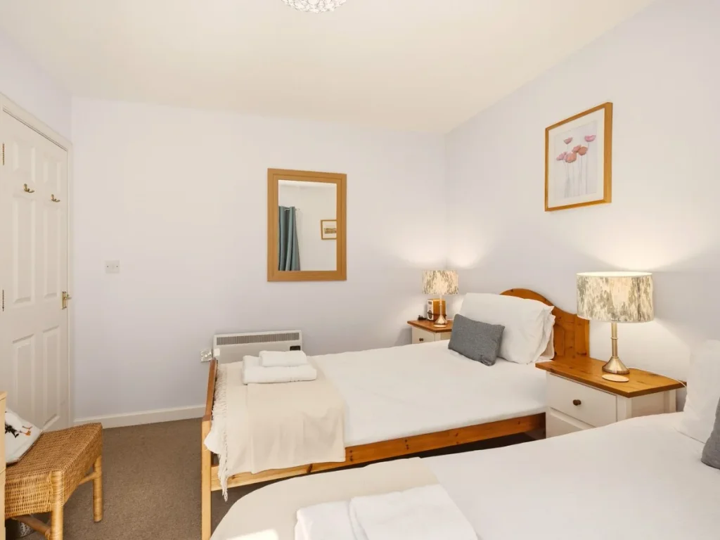 Twin bedroom with two single beds, bedside lamps and wall mirror